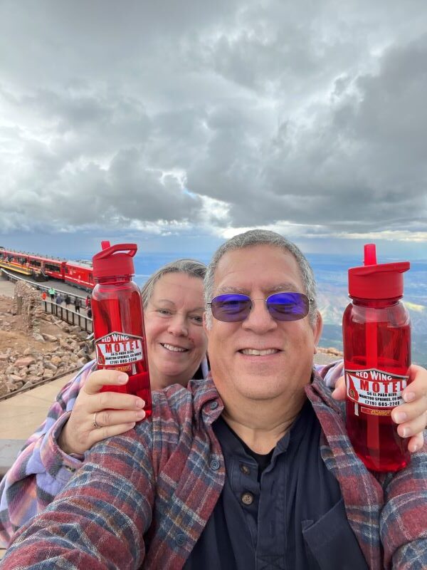 Man and woman holding Red Wing Motel water bottles on top of mountain
